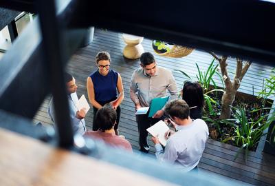 view from above of 5 coworkers standing in a circle talking
